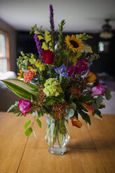 Verschiedene Blumen in Glasvase auf Holztisch zu Hause - CAVF38398