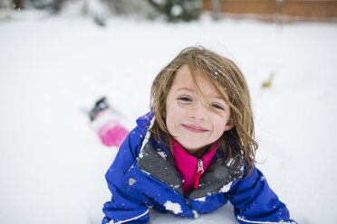 Portrait of cute girl lying on snow covered field - CAVF38436