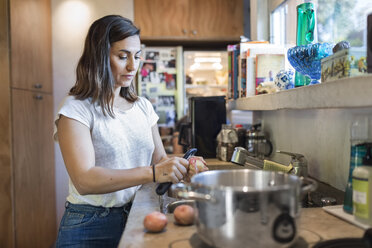 Woman peeling potato at kitchen counter - MASF03761