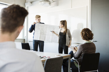 Junge Frau zeigt Flipchart an Freunde und Professor im Klassenzimmer - MASF03768