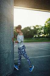 Woman stretching by column on street - MASF03777