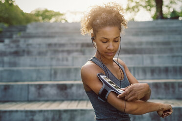 Frau benutzt Smartphone-Armband beim Sport - MASF03781