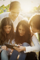Teenager nutzen gemeinsam ein digitales Tablet im Freien - MASF03784