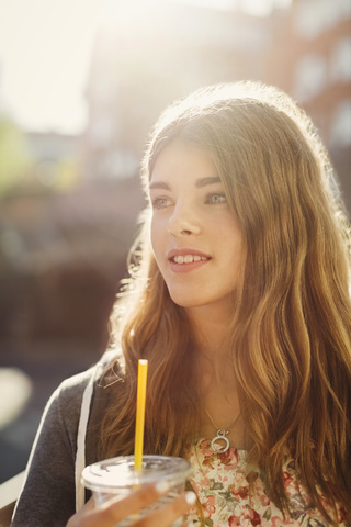 Thoughtful teenage girl holding disposable glass outdoors stock photo