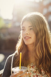 Thoughtful teenage girl holding disposable glass outdoors - MASF03792