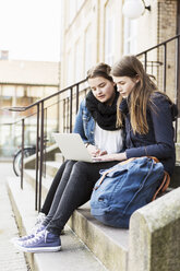 Junge Freundinnen benutzen Laptop auf den Stufen vor der Schule - MASF03805