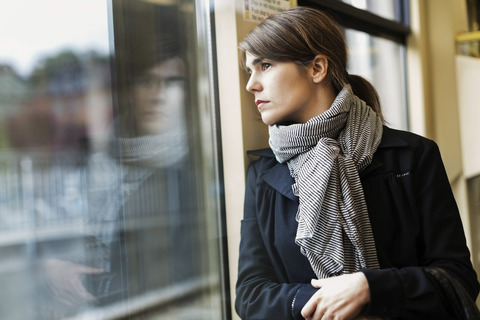 Nachdenkliche junge Frau schaut aus dem Straßenbahnfenster, lizenzfreies Stockfoto