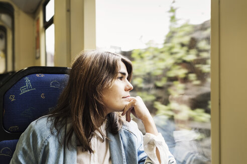 Nachdenkliche junge Frau schaut durch ein Straßenbahnfenster - MASF03813