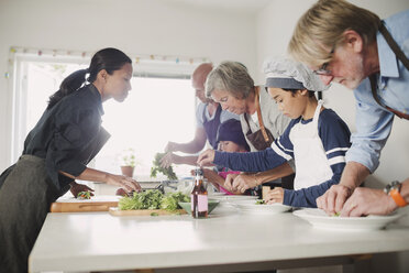 Woman guiding family in preparing Asian food at kitchen - MASF03833