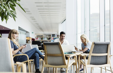 Universitätsstudenten nutzen Technologien am Tisch in der Bibliothek - MASF03836