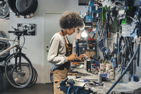 Seitenansicht einer Mechanikerin bei der Arbeit in einer Fahrradwerkstatt - MASF03866