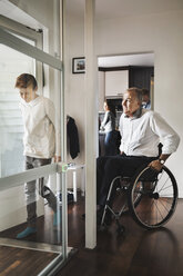 Son and father entering wheelchair lift at home - MASF03876