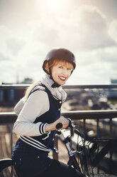Seitenansicht Porträt der glücklichen Geschäftsfrau stehend mit Fahrrad auf Brücke - MASF03880