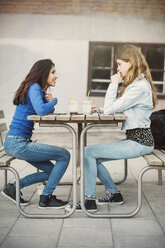 Seitenansicht von weiblichen Teenagern, die sich an einem Tisch im Freien unterhalten - MASF03899