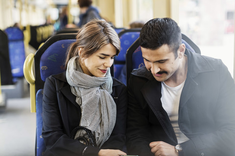 Lächelndes Paar blickt in der Straßenbahn nach unten, lizenzfreies Stockfoto