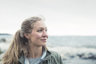 Lächelnde junge Frau, die am Meer gegen den Himmel wegschaut - MASF03930