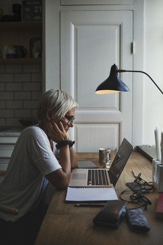 Side view of female designer working late at home office stock photo
