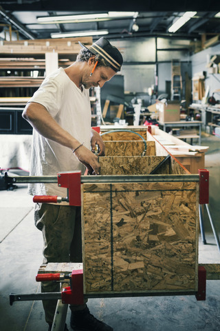 Seitenansicht eines Tischlers bei der Herstellung von Möbeln in der Werkstatt, lizenzfreies Stockfoto