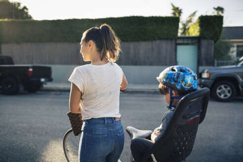 Rückansicht einer Frau mit Fahrrad und Sohn auf dem Rücksitz im Freien - MASF03979