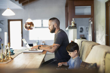 Side view of father and son using technologies at dining table - MASF03981
