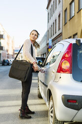 Side view of businesswoman opening car door on street - MASF03988