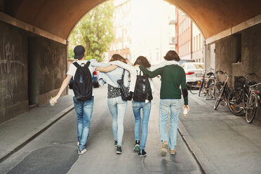 Rückansicht von Teenagern, die mit den Armen in einem Tunnel laufen - MASF03994