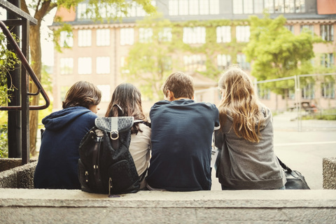 Rückansicht von Jugendlichen, die auf Stufen im Freien sitzen, lizenzfreies Stockfoto
