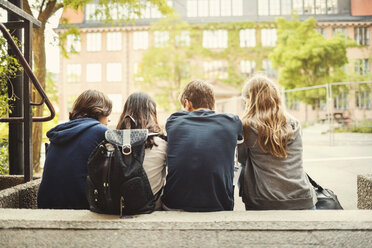 Rear view of teenagers sitting on steps outdoors - MASF03996