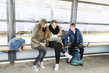 Schüler benutzen Laptop auf einer Bank im Bahnhof - MASF04004