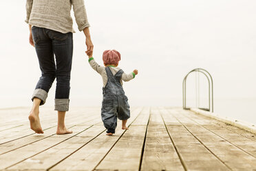 Rear view of mother walking with daughters on pier against clear sky - MASF04008