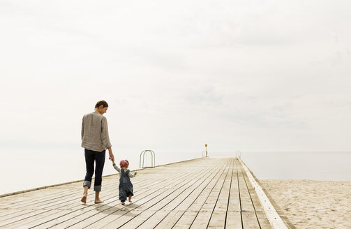 Rückansicht von Mutter und Tochter, die auf dem Pier am Strand gegen den Himmel laufen - MASF04009
