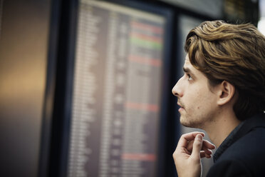 Side view of businessman reading arrival departure board at airport - MASF04017