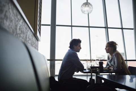 Seitenansicht von Geschäftsleuten, die sich in einem Café im Flughafen unterhalten, lizenzfreies Stockfoto