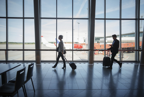 Seitenansicht von Geschäftsleuten mit Gepäck auf dem Flughafen, lizenzfreies Stockfoto