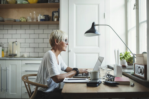 Side view of designer using laptop at home office - MASF04024