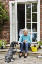 Ältere Frau mit Hund vor der Tür sitzend - MASF04029