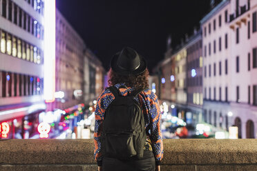Rückansicht einer Frau mit Rucksack auf einer Brücke in einer nächtlichen Stadt - MASF04030