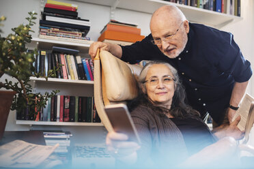 Senior couple taking selfie through mobile phone at home - MASF04036