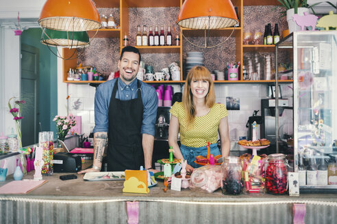 Portrait of male and female baristas standing at cafe counter - MASF04041