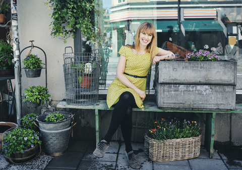 Portrait of happy owner leaning on crate outside plant shop stock photo