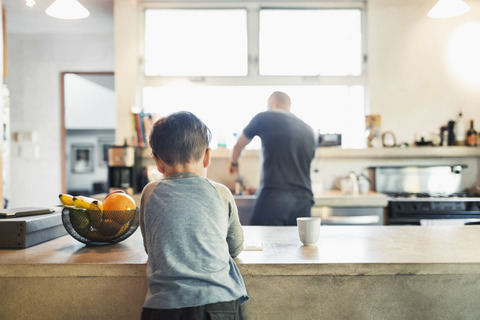 Rear view of father and son in kitchen stock photo