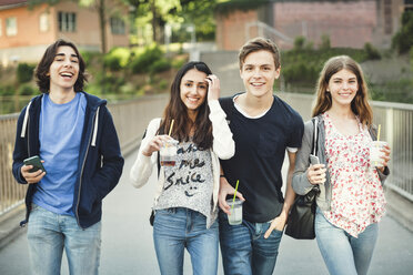 Porträt von glücklichen Teenagern mit Einwegbrillen und Smartphones auf einer Brücke - MASF04075