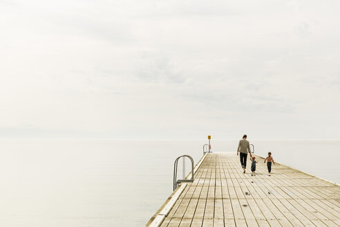 Rückansicht einer Familie, die auf einem Pier am Meer spazieren geht, gegen den Himmel - MASF04089