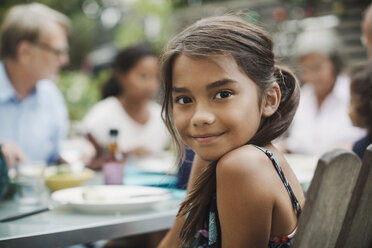 Portrait of smiling girl sitting with family at outdoor dining table - MASF04091