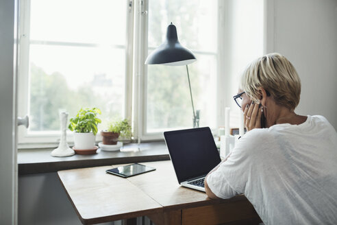 Rear view of industrial designer using laptop at home office - MASF04101