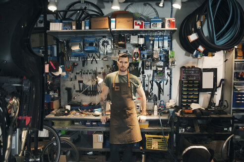 Porträt eines selbstbewussten Mechanikers, der sich auf eine Werkbank stützt - MASF04110