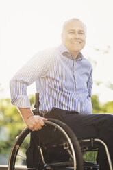 Portrait of happy man sitting in wheelchair outdoors - MASF04111