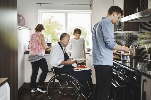 Parents and children preparing food together in kitchen stock photo