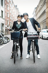Portrait of happy business people with bicycles standing on city street - MASF04113