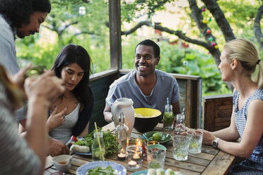 Multi-ethnic friends having food at porch in log cabin - MASF04141